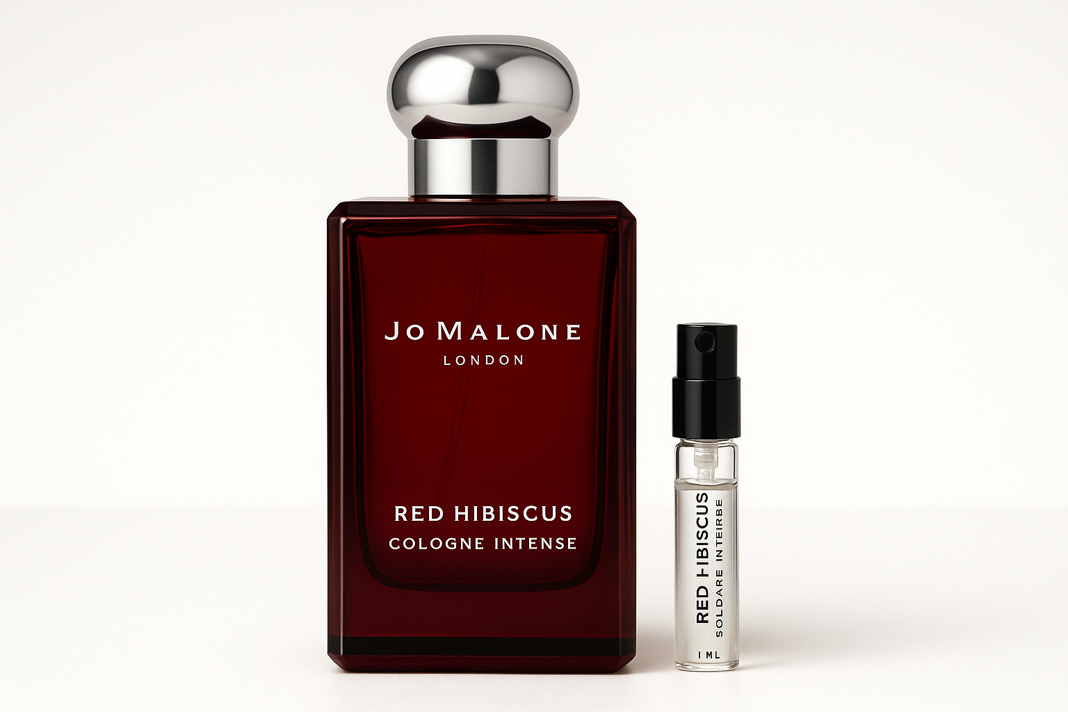 Échantillon de 1 ml de Cologne Intense Jo Malone Red Hibiscus à côté d'un flacon de parfum de 100 ml de Cologne Intense Jo Malone Red Hibiscus qui a une écriture blanche sur un flacon rouge foncé